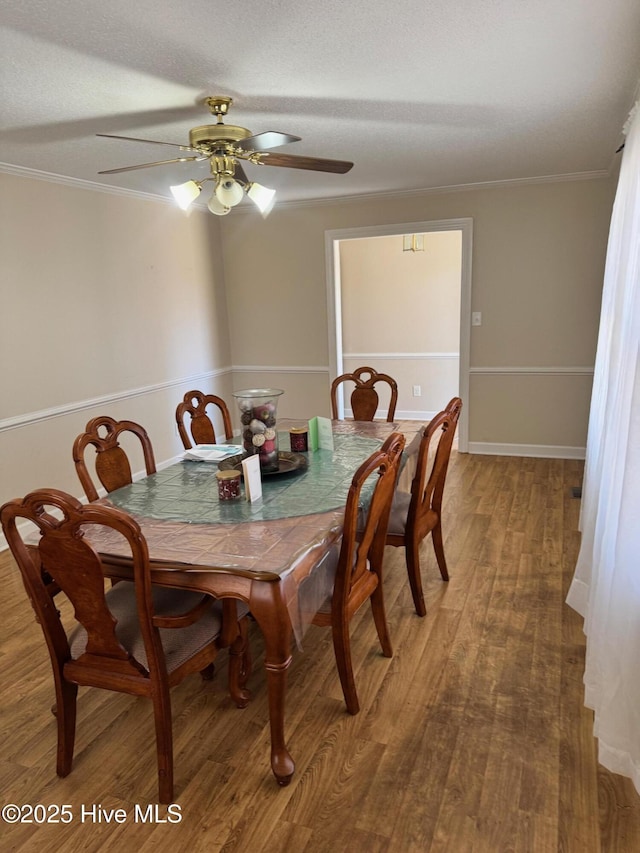 dining area with a textured ceiling, ceiling fan, wood finished floors, baseboards, and ornamental molding