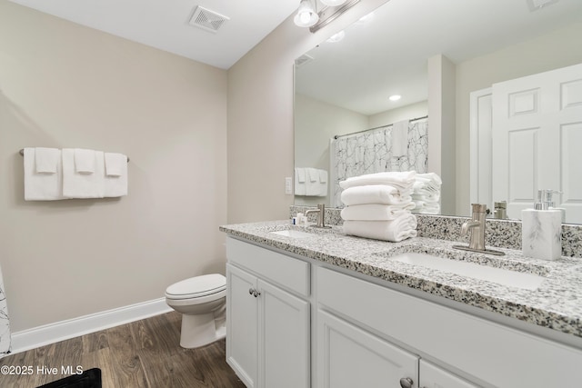 full bath with visible vents, wood finished floors, a sink, and toilet