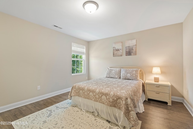 bedroom with visible vents, baseboards, and wood finished floors