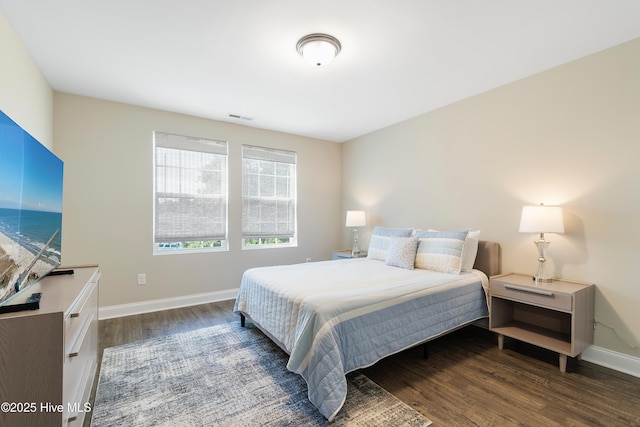 bedroom with baseboards, visible vents, and wood finished floors