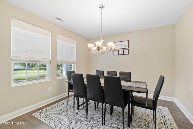 dining area featuring an inviting chandelier, baseboards, visible vents, and dark wood finished floors