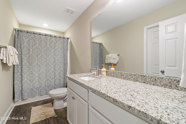 bathroom with visible vents, a shower with shower curtain, toilet, wood finished floors, and vanity