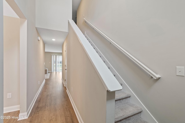 stairs featuring a high ceiling, baseboards, and wood finished floors