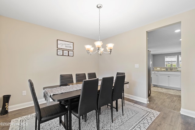 dining space with an inviting chandelier, wood finished floors, and baseboards