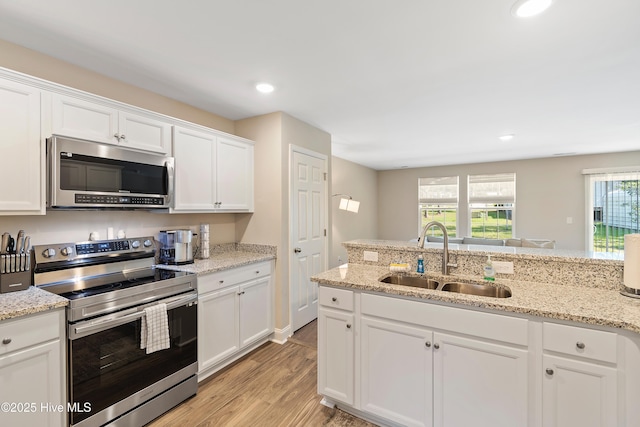 kitchen with recessed lighting, appliances with stainless steel finishes, light wood-style floors, white cabinetry, and a sink