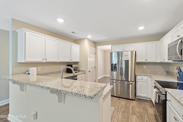 kitchen featuring stainless steel appliances, white cabinetry, and light wood-style floors