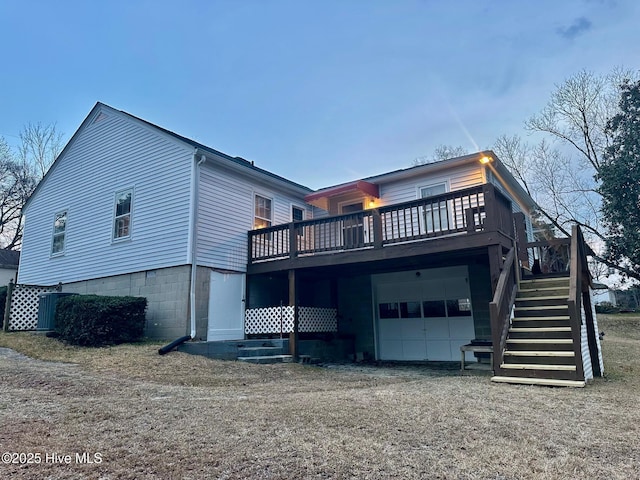 rear view of property with an attached garage, dirt driveway, stairway, and a deck