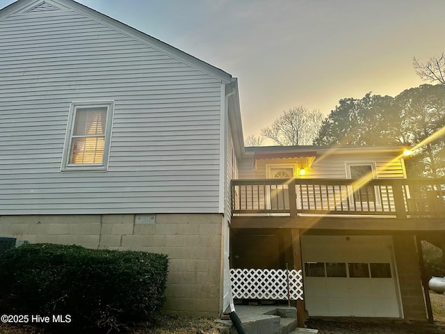 property exterior at dusk featuring a garage and a balcony