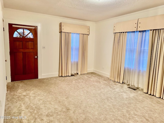 entryway featuring a textured ceiling, light carpet, visible vents, baseboards, and crown molding