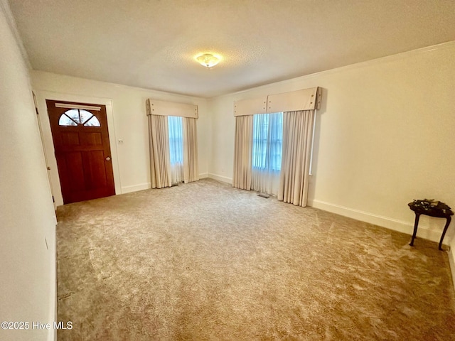 entrance foyer featuring light colored carpet, a textured ceiling, and baseboards