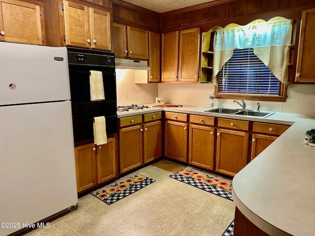 kitchen with white appliances, brown cabinets, light countertops, under cabinet range hood, and a sink