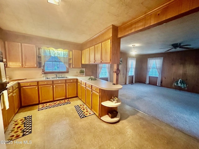 kitchen featuring light colored carpet, a peninsula, a sink, open floor plan, and light countertops