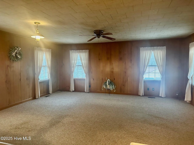 empty room featuring carpet, plenty of natural light, visible vents, and ceiling fan