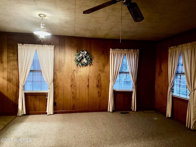 unfurnished dining area with carpet floors, plenty of natural light, and a ceiling fan