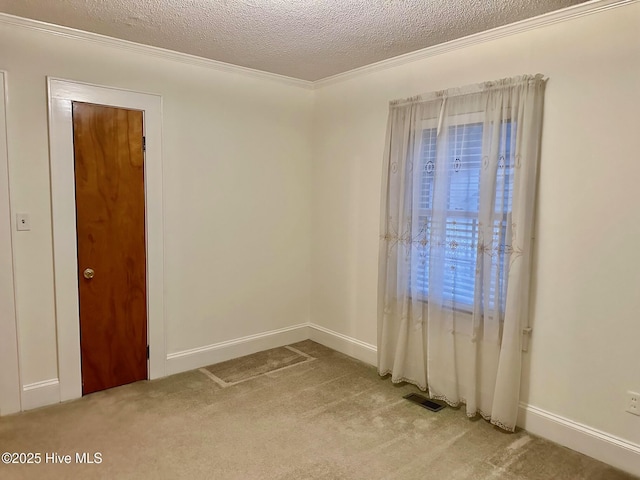 empty room featuring visible vents, ornamental molding, light carpet, a textured ceiling, and baseboards