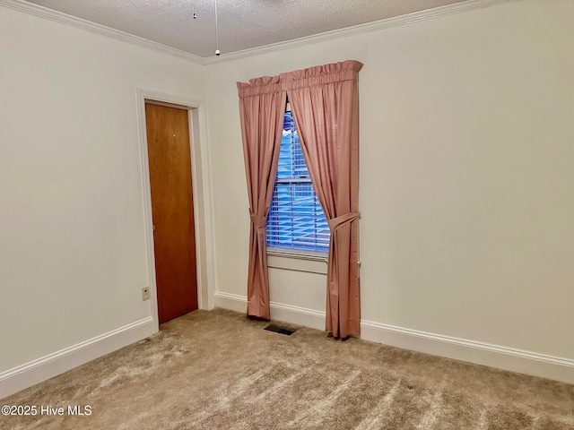 empty room featuring carpet floors, crown molding, visible vents, a textured ceiling, and baseboards