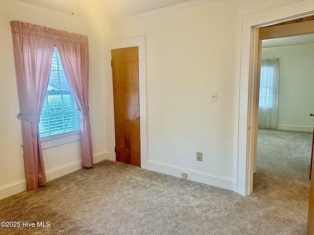 unfurnished bedroom featuring carpet floors, crown molding, and baseboards