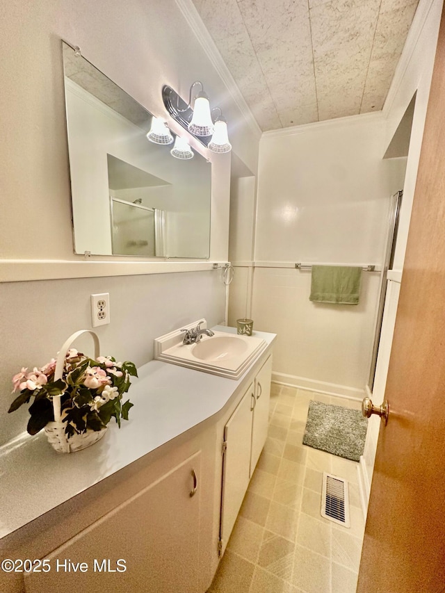 bathroom featuring vanity, baseboards, visible vents, walk in shower, and crown molding