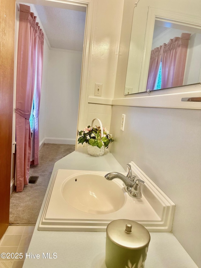 bathroom with visible vents, a sink, and a textured ceiling