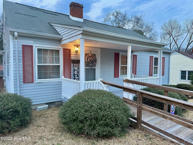 exterior space with crawl space, roof with shingles, a chimney, and covered porch