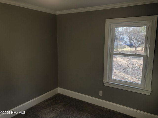 empty room with baseboards, dark colored carpet, and crown molding