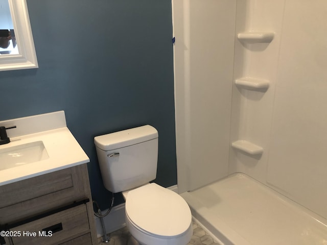 bathroom featuring toilet, a shower, and vanity