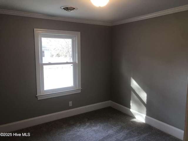 spare room featuring dark colored carpet, crown molding, and baseboards