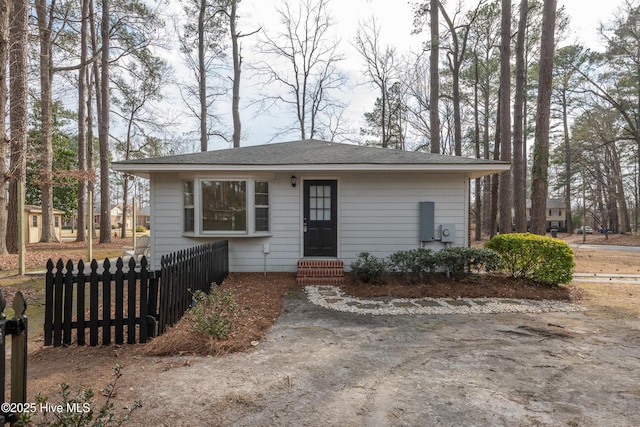 view of front facade with entry steps, roof with shingles, and fence