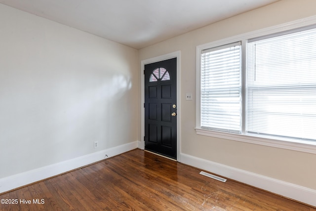 foyer with baseboards, visible vents, and dark wood finished floors