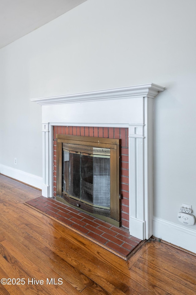 interior details featuring a brick fireplace, wood finished floors, and baseboards