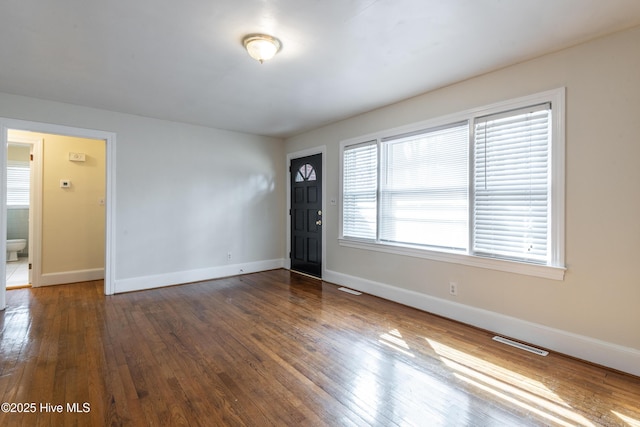 foyer entrance with wood-type flooring, visible vents, and baseboards