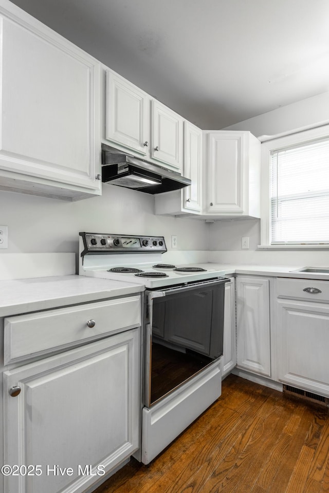 kitchen with dark wood-style floors, white electric stove, light countertops, white cabinets, and under cabinet range hood