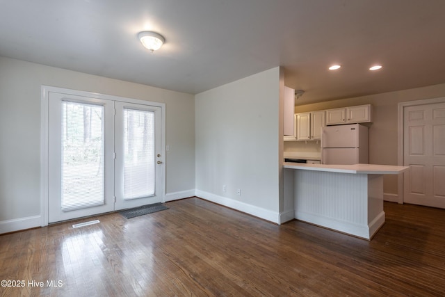 kitchen with a peninsula, visible vents, light countertops, freestanding refrigerator, and dark wood-style floors