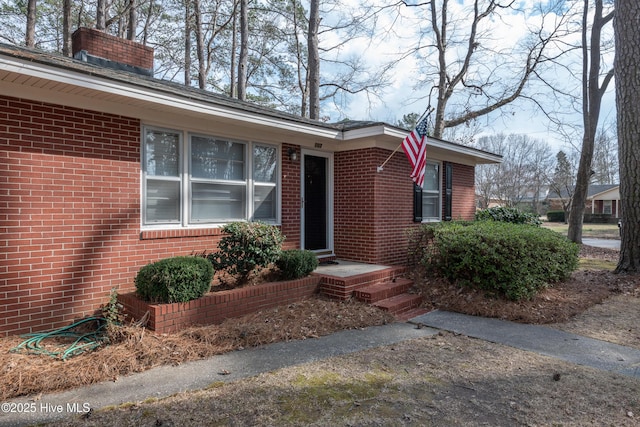 property entrance featuring brick siding and a chimney