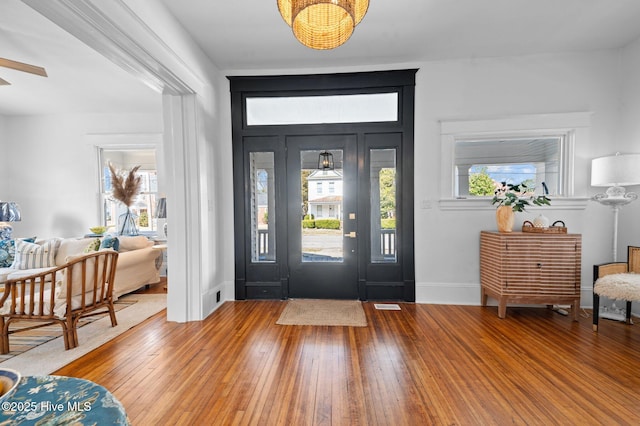 foyer entrance featuring baseboards, visible vents, and hardwood / wood-style floors