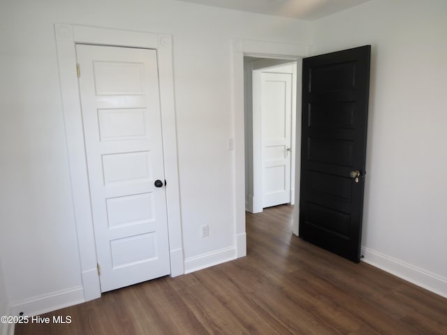 unfurnished bedroom with dark wood-style floors and baseboards