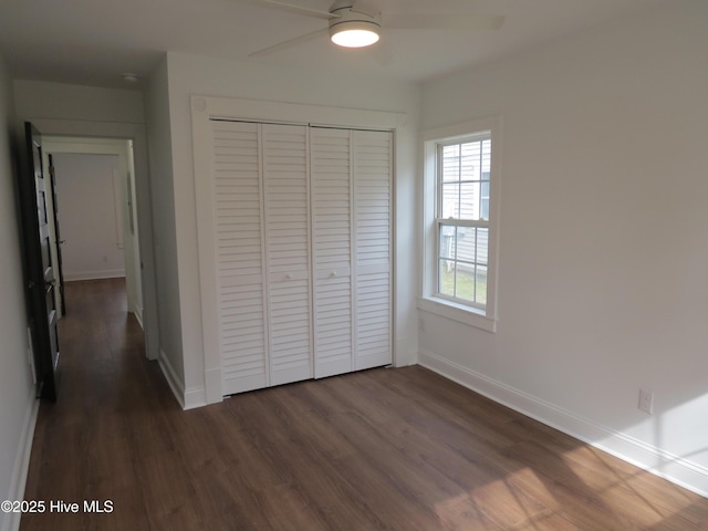 unfurnished bedroom featuring a closet, dark wood finished floors, a ceiling fan, and baseboards