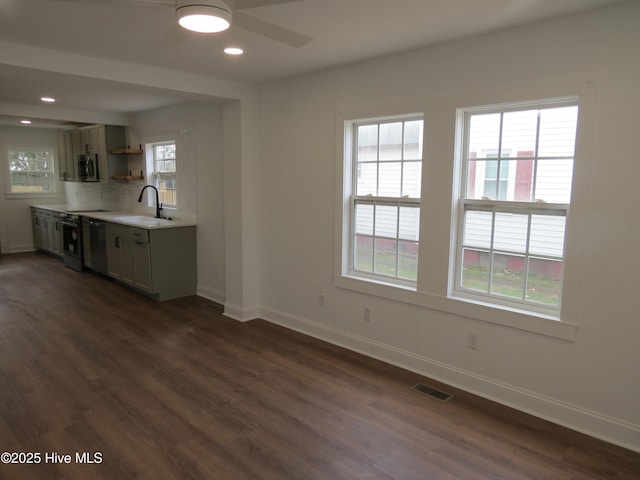 kitchen featuring baseboards, visible vents, stainless steel microwave, and a sink