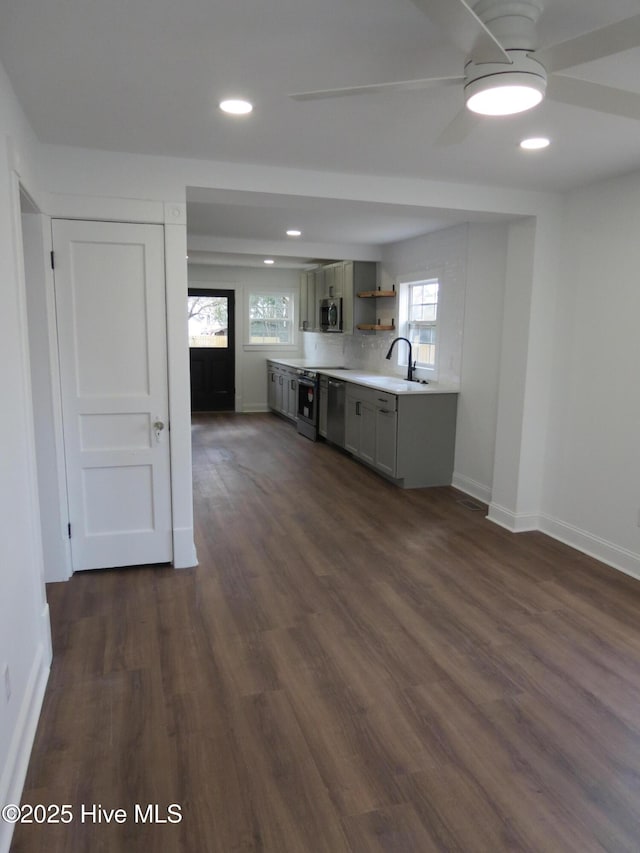 kitchen with baseboards, stainless steel microwave, dark wood-type flooring, light countertops, and open shelves