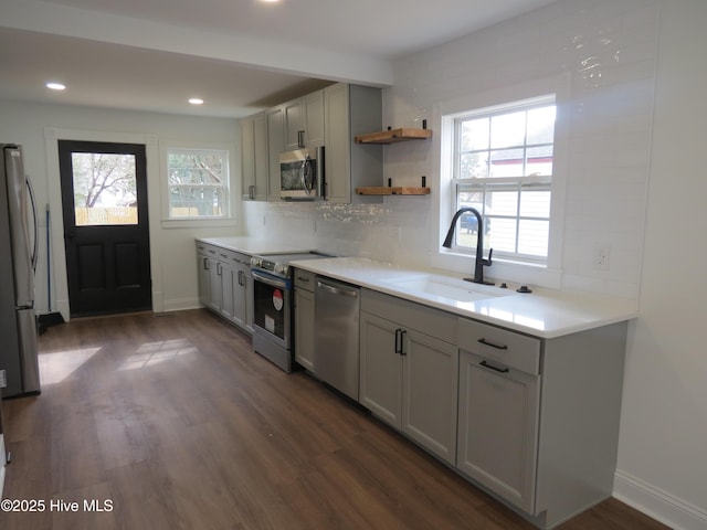 kitchen with appliances with stainless steel finishes, a wealth of natural light, a sink, and decorative backsplash