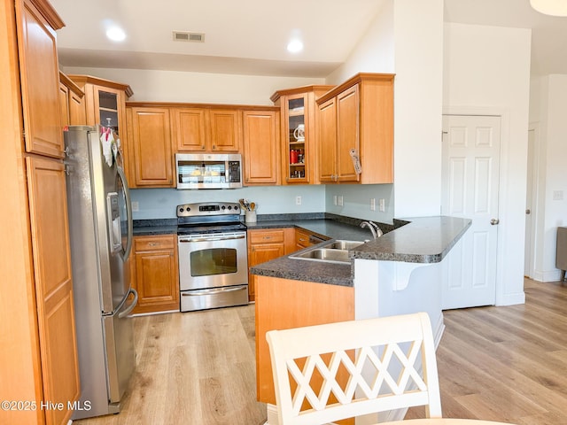 kitchen with visible vents, appliances with stainless steel finishes, brown cabinets, a peninsula, and a sink