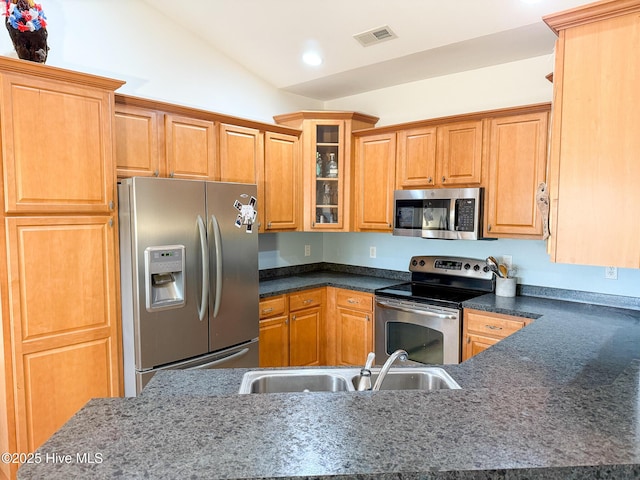 kitchen featuring lofted ceiling, dark countertops, visible vents, appliances with stainless steel finishes, and a sink