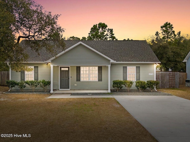 single story home with a shingled roof, fence, and a front lawn