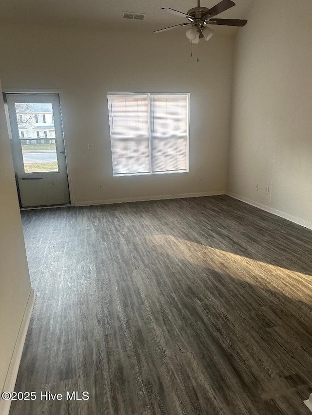 empty room featuring ceiling fan, dark wood-type flooring, visible vents, and baseboards