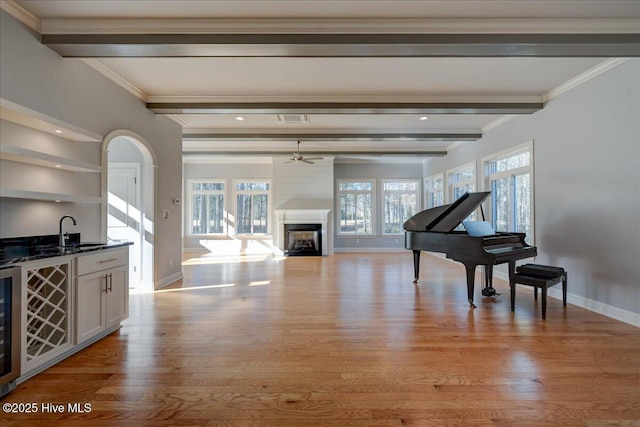 living room with light wood-type flooring, beamed ceiling, a fireplace, and baseboards