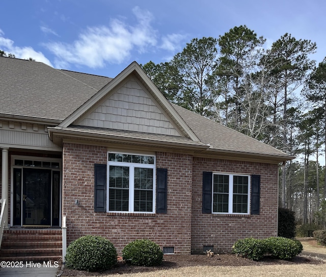 view of home's exterior featuring entry steps, crawl space, brick siding, and roof with shingles