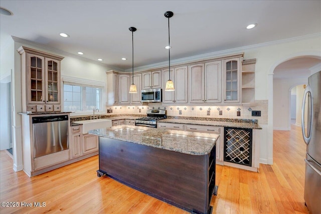kitchen featuring appliances with stainless steel finishes, a sink, arched walkways, wine cooler, and glass insert cabinets
