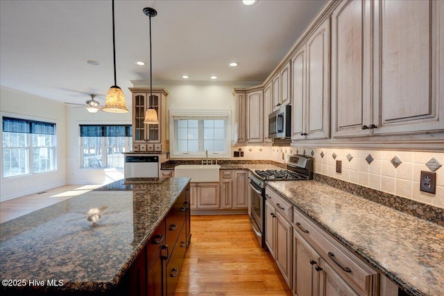 kitchen with a sink, dark stone countertops, stainless steel appliances, backsplash, and glass insert cabinets