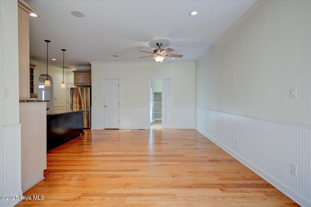 unfurnished living room featuring a ceiling fan, recessed lighting, wainscoting, and light wood-style floors