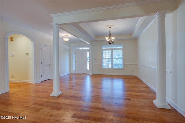 entrance foyer featuring ornate columns, crown molding, a raised ceiling, and light wood-style floors